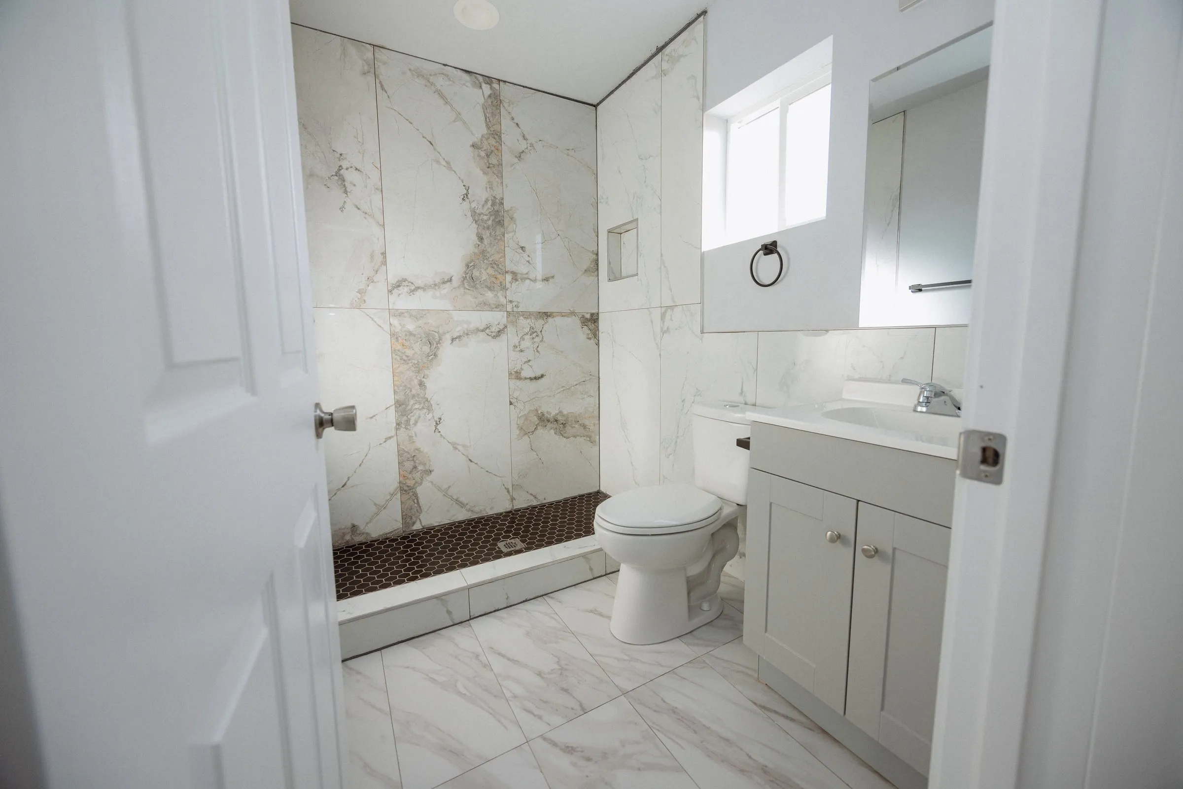 Bathroom finished in marble-effect tile, with a glass shower enclosure and a wall-hung vanity
