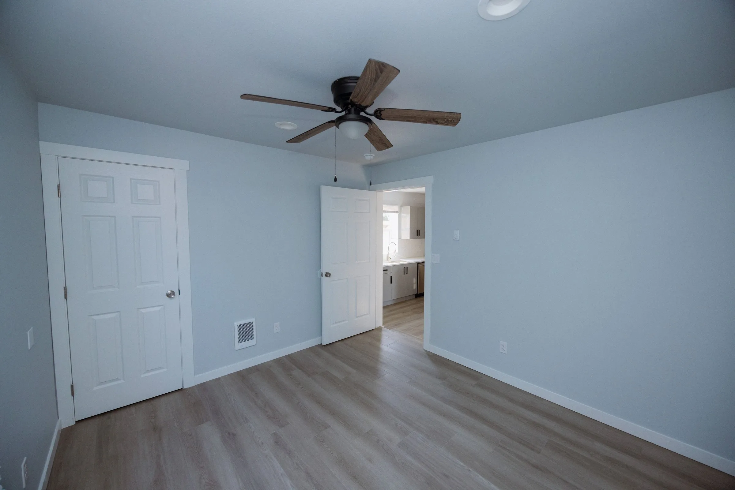 Bedroom with a ceiling fan and a doorway through to the bathroom