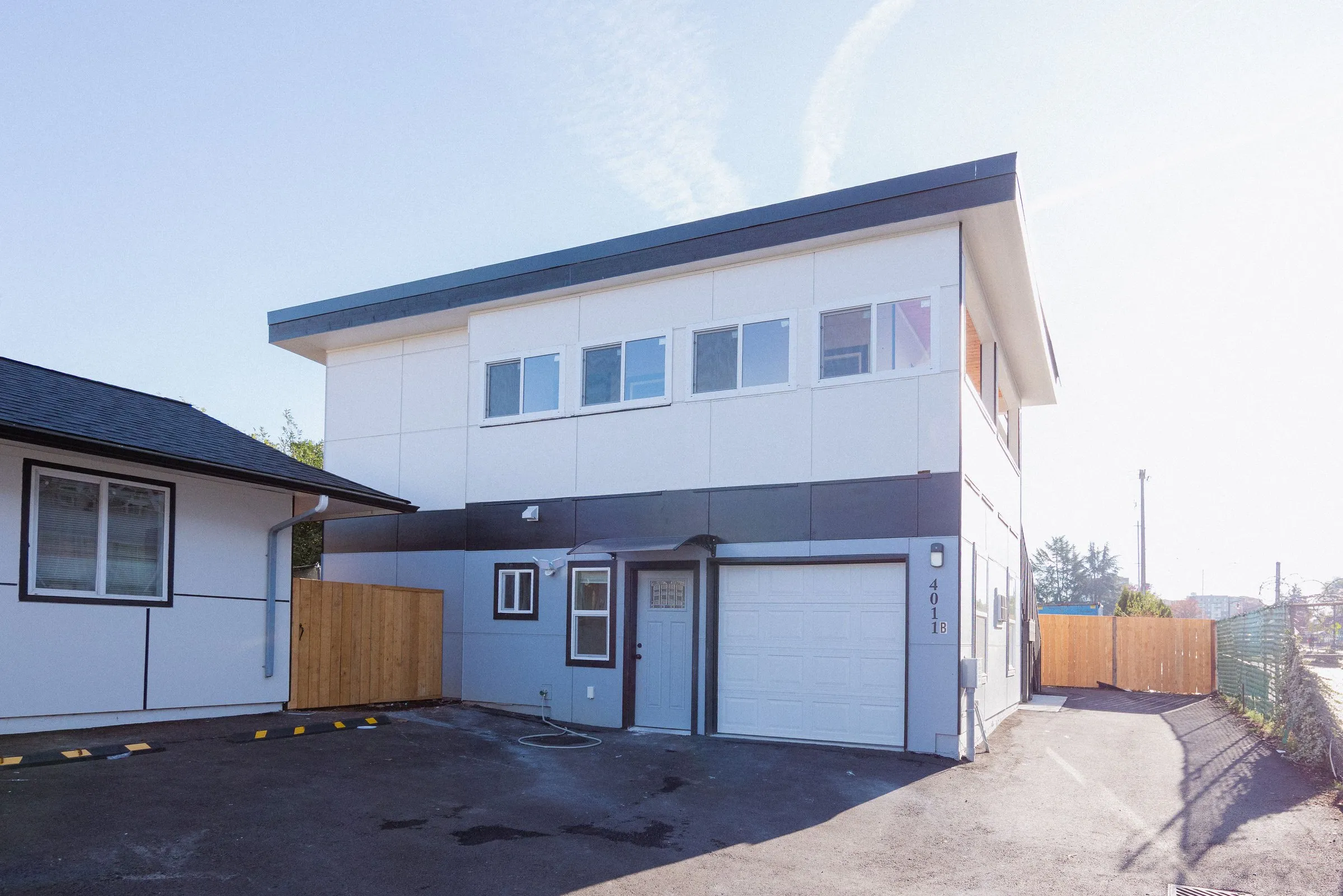 Street view of the finished building alongside the main house, with the garage doors facing the driveway