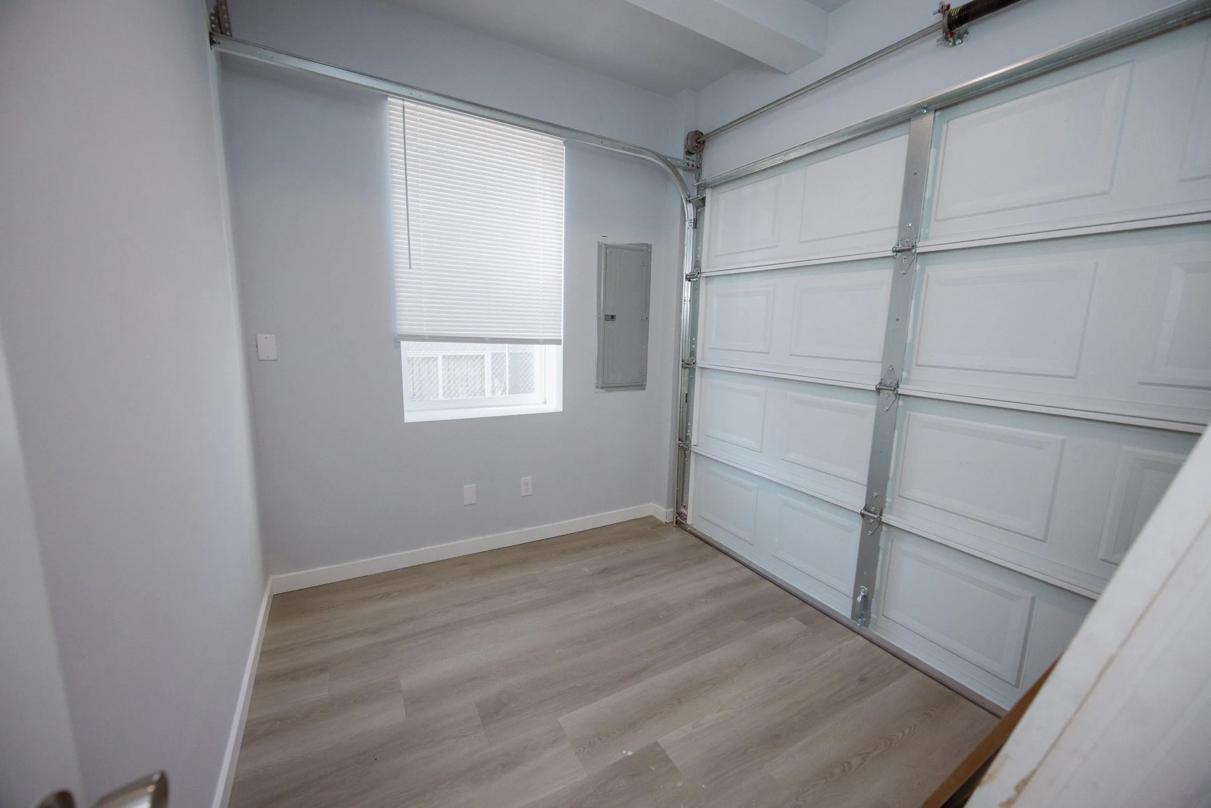 Interior of the attached garage with the sectional door closed and the electrical panel on the side wall