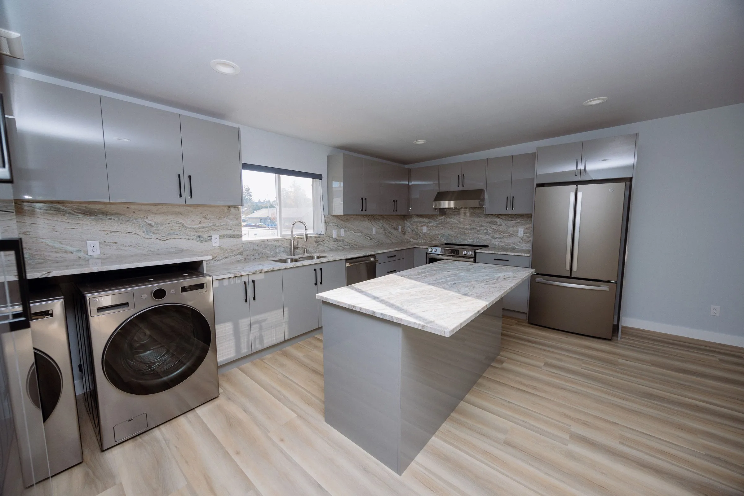 Kitchen with a full-size stacked washer and dryer built into the cabinetry run, alongside the island and refrigerator