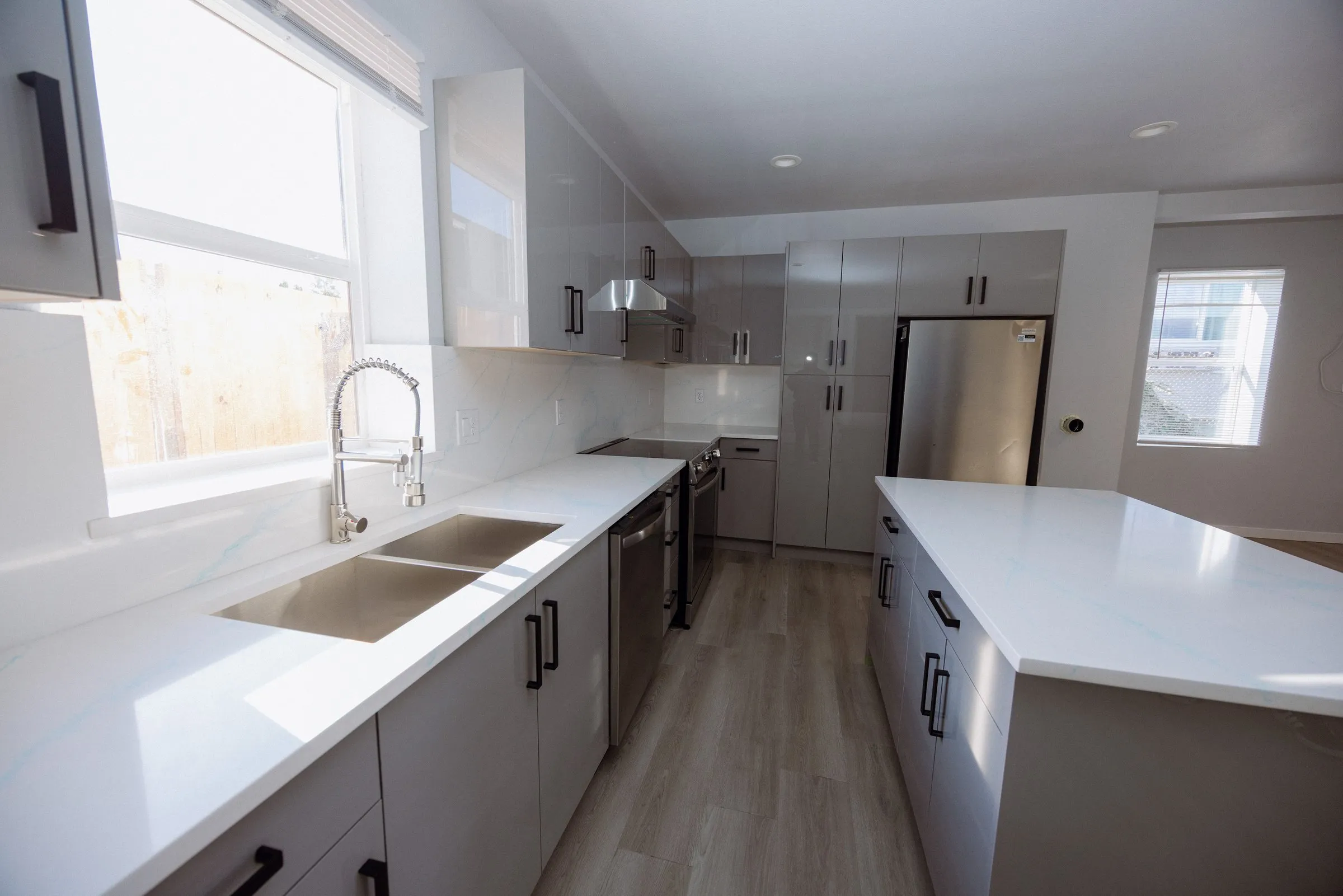 Kitchen counter run with an undermount sink beneath the window, quartz worktops and a stainless range