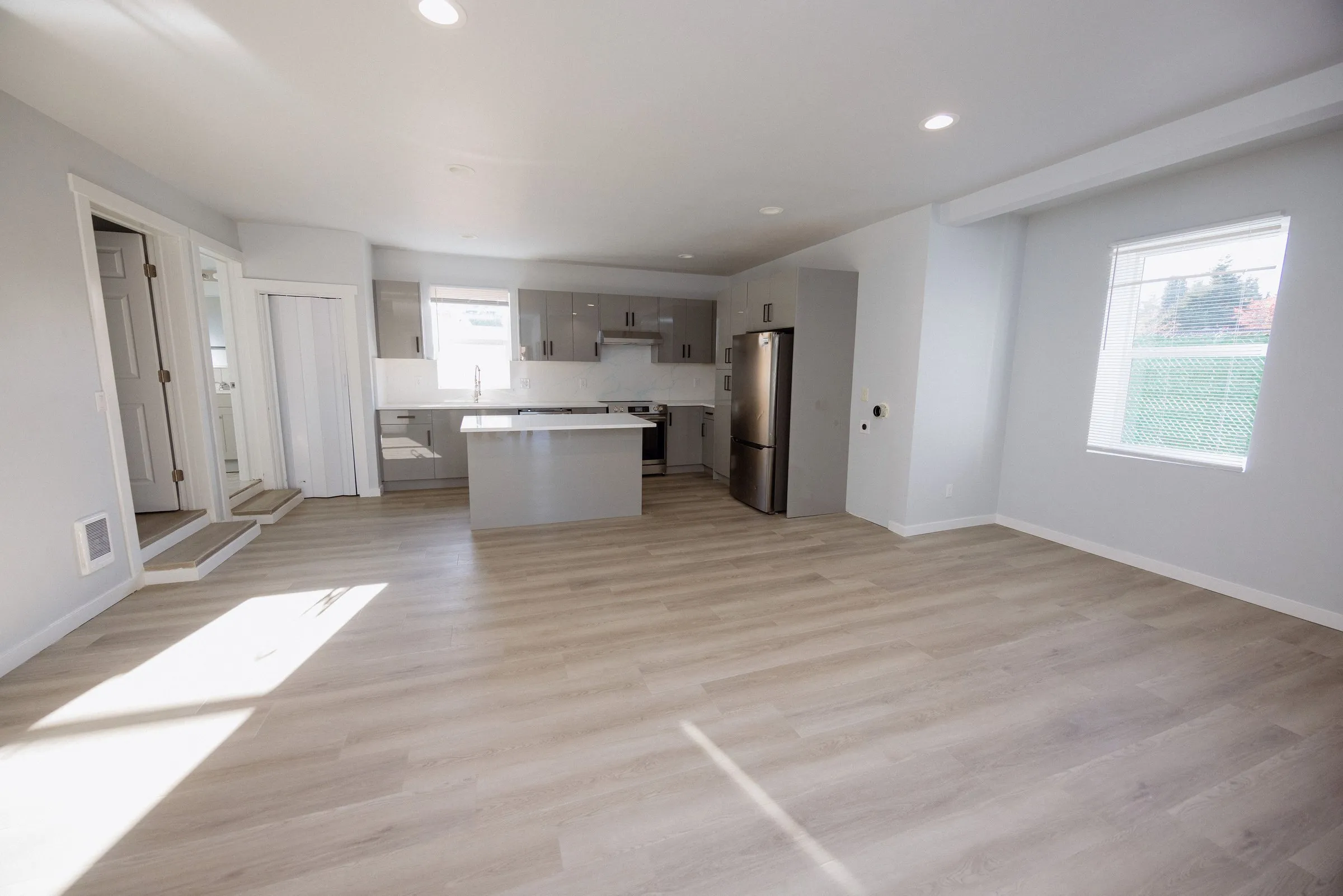 Living area looking toward the kitchen island, with recessed lighting and light wood-effect flooring throughout