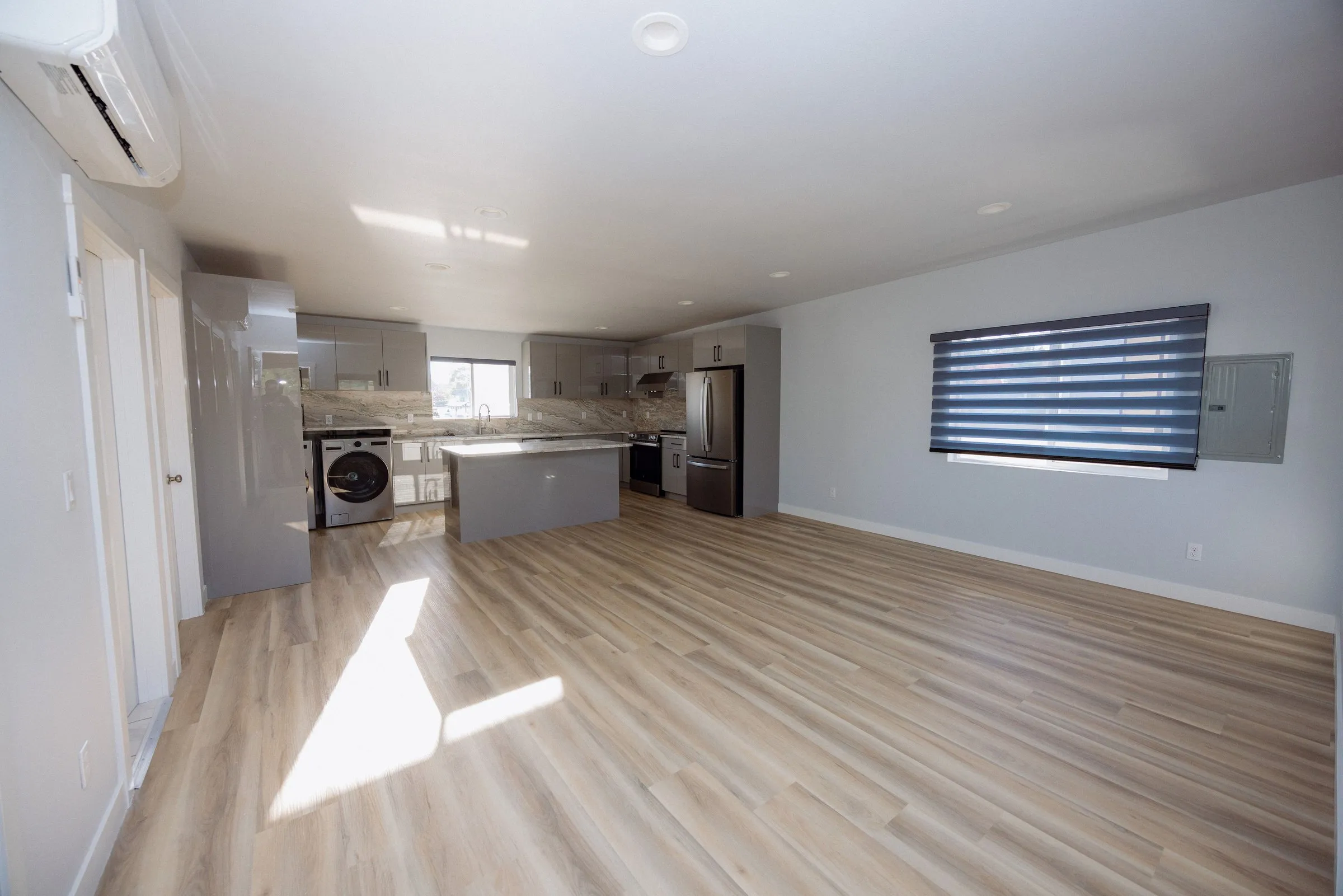 Open-plan living area with the kitchen along the far wall and a ductless mini-split head mounted above