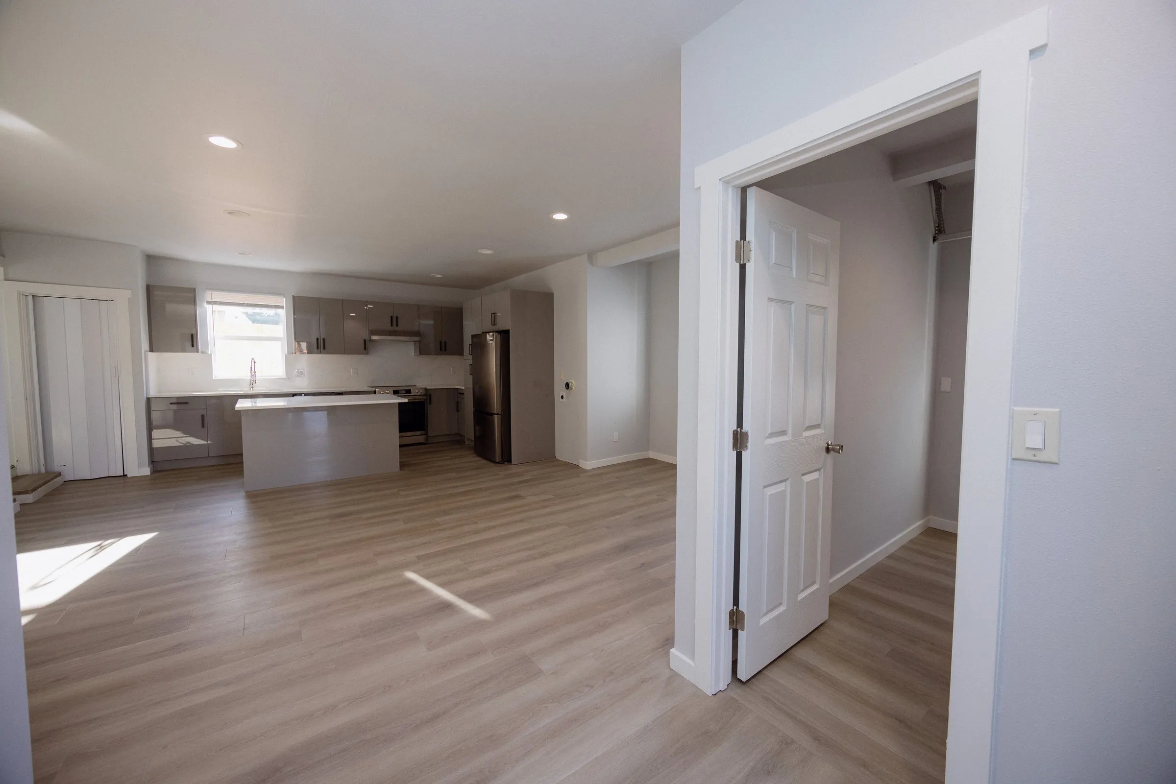 Living area with a doorway through to the bedroom, kitchen island visible beyond